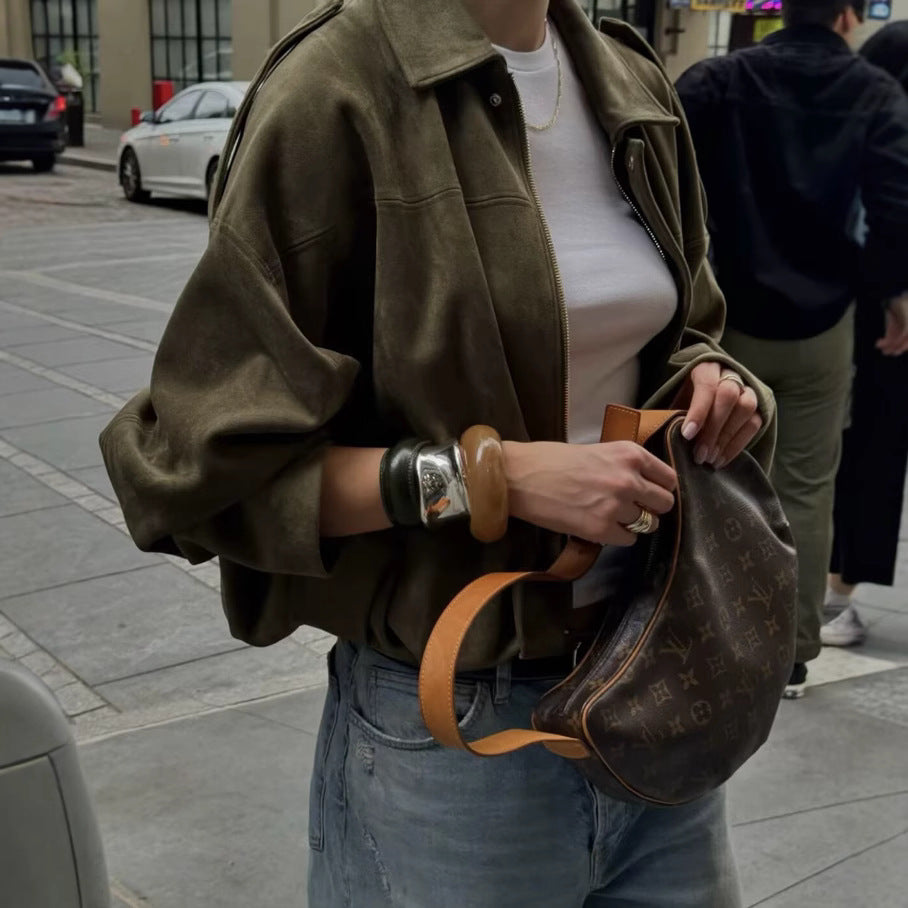 Woman styling an army green oversized faux suede bomber jacket with denim